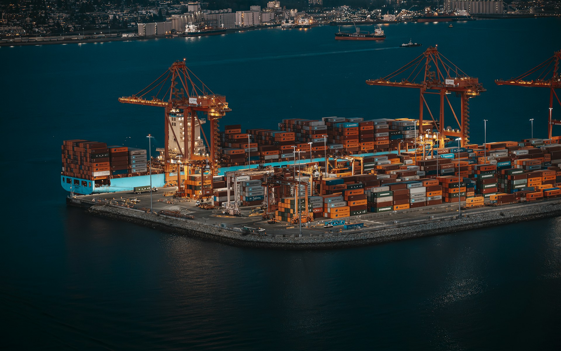 Aerial night view of a container terminal with cranes and cargo ship at port